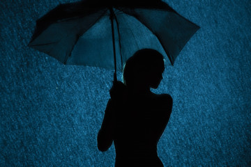 silhouette of the figure of a young girl with an umbrella in the rain