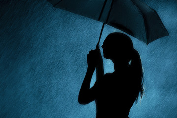 silhouette of the figure of a young girl with an umbrella in the rain