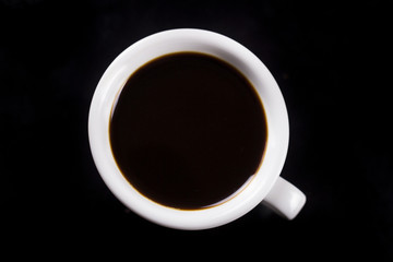 Black coffee in white cup on dark surface. Close up.