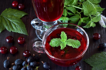 Berry kissel in a glass cup topped with mint against the dark background