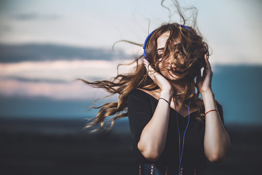 portrait of a beautiful girl in headphones listening to music on nature