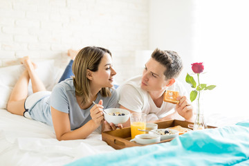 Man And Woman Talking While Having Food By Breakfast Tray