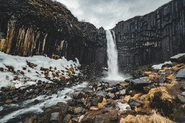 Dramatic morning view of famous Svartifoss (Black Fall) Waterfall. Colorful summer sunrise in...