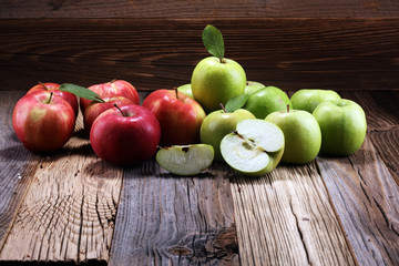 Ripe red apples with leaves on wooden background.