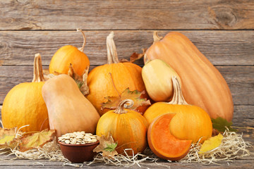 Orange pumpkins with dry leafs and seeds on grey wooden table