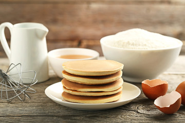 Tasty pancakes with eggs, flour and cup of tea on grey wooden table
