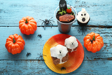 Halloween gingerbread cakes with pumpkin on blue wooden table