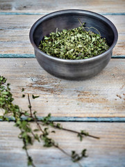 Dried thyme - thymus vulgaris in metal bowl on wooden table. Copy space.