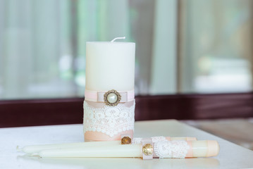 The white candles decorated with a tape with a brooch and lace.