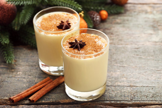 Eggnog in glasses with cinnamon and star anise on wooden table