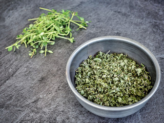 Dried thyme - thymus vulgaris in metal bowl on dark grey table. Copy space.