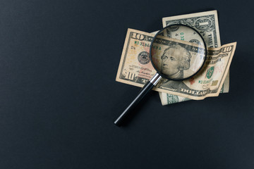 Magnifying glass and money on black background. Paper currency. Looking For Money. Concept of search. Top view. Flat lay