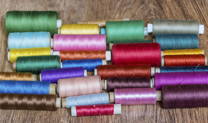 Multi Colored Thread Yarns on Wooden Background 