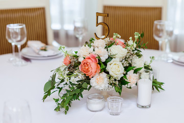 Very graceful and beautiful composition from fresh flowers. Wooden number of a table and a candle
