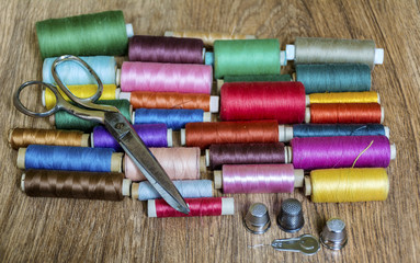 Multi Colored Thread Yarns and Vintage Scissors on Wooden Background 