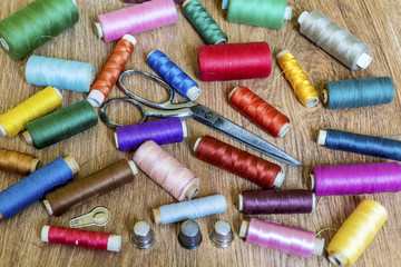 Multi Colored Thread Yarns and Vintage Scissors on Wooden Background 