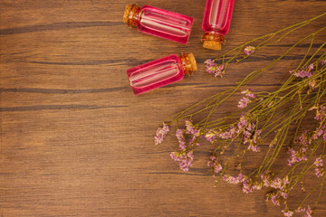 Flat lay organic essential oil and flower with copy space on brown wooden background