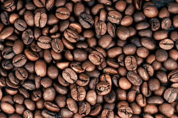 Roasted coffee beans background. Brown roasted coffee beans. Macro photo seed on dark background. Top view.