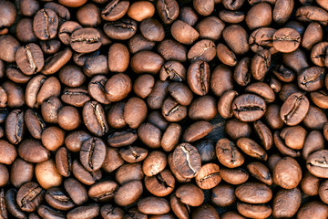 Roasted coffee beans background. Brown roasted coffee beans. Macro photo seed on dark background. Top view.