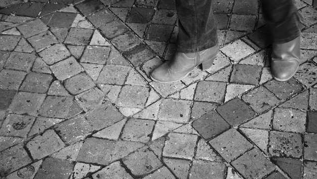 Castle visiting. Closeup of young woman legs in motion on terracotta tile floor. Sightseeing background. Black and white photo.