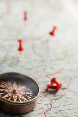 Closeup of a Compass on a Map with Pushpins