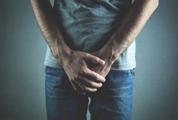 Caucasian man with hands holding his crotch. Inflammation of the prostate, erection problems