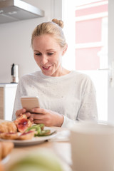 Woman looking down at her phone and smiling