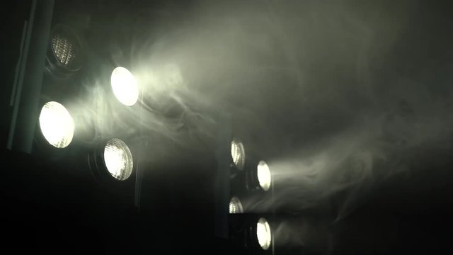 Eight spotlights flicker in a smoky room