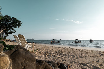 Two free beach chairs on the coastline of phi phi island, thailand in front of indian ocean with...