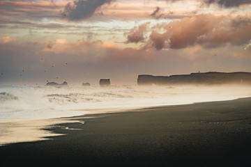 Sunrise at famous Black Sand Beach Reynisfjara in Iceland. Windy Morning. Ocean Waves. Colorful Sky. Morning Sunset.