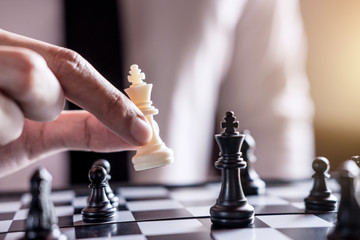 Hand of confident businessman use king chess piece white playing chess game to development analysis...