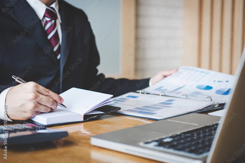 Poster Businessman writing report and pointing at graph chart data to analysis use for plans to improve quality, business finances and accounting concept