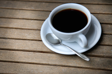 White cup with brown coffee on a wooden table.