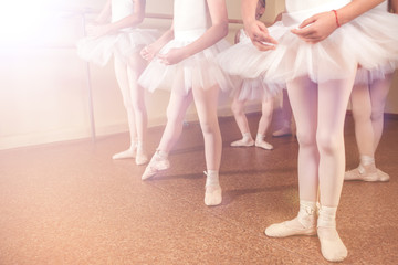 Fototapeta na wymiar Ballet background, training of young ballerinas. Little dancers feet in pointe shoes doing exercises.