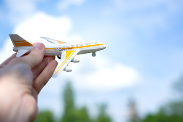 toy airplane in hand on beautiful sky with cloud background in concept travel around the world. happy trip.