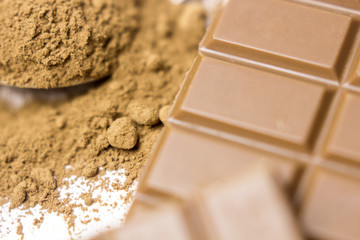 Chocolate bar pieces and cocoa powder on white background. Brown chocolate powder.