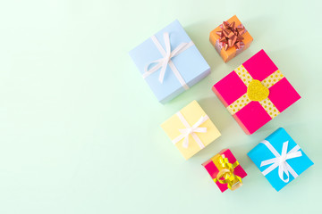 Different colored gift box on pastel light green background. Top view of various present boxes on minimal background. Birthday, Christmas, wedding, valentine, romantic gifts