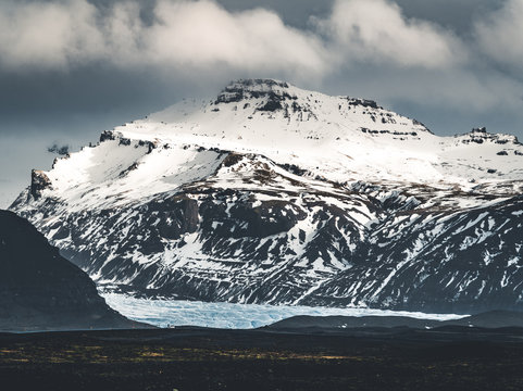 Road leading towards huge glacier and mountains in Iceland Vatnajokull glacier aerial drone image with street highway and clouds and blue sky. Dramatic winter scene of Vatnajokull National Park