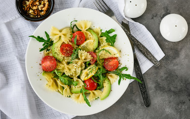 Salad with pasta, avocado, tomato and arugula.