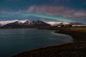 Obraz premium Northern lights on the Diamond beach in south east Iceland, Jokursarlon Vik ice rocks ocean
