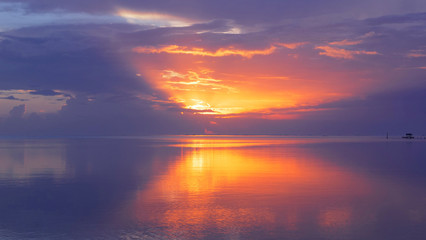 Breathtaking shot of the endless horizon and calm ocean at orange lit sunset.