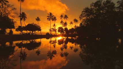 AERIAL: Flying over a small lake near the picturesque beach at golden sunrise.