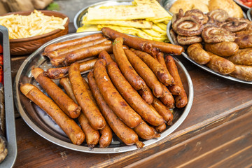 fried sausages on an open fire on a metal plate stand on a wooden table