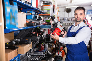 Adult male is standing with puncher in tools store.