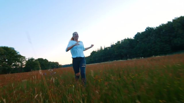 Ecstatic young woman skipping carefree through a field toward camera, SLOWMO. Assen, Netherlands.