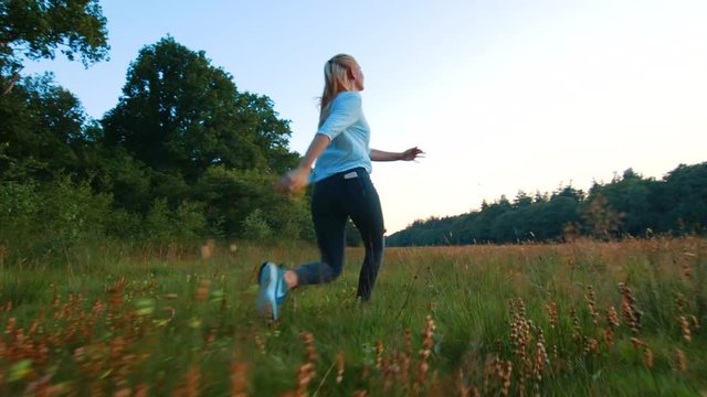 Joyful young woman skipping, spinning, and prancing through a meadow, Low Angle Slowmo Tracking Shot. Assen, Netherlands.