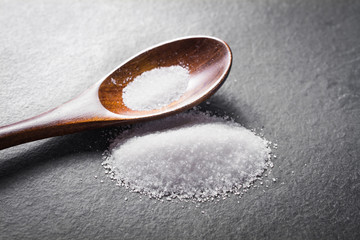 Macro Of A Wooden Spoon And A Pile of White Spilled Sugar On Slate Stone, Side View