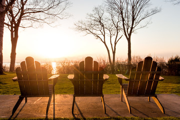 A row of Adirondack chairs at sunset