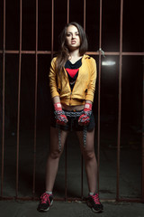 Naklejka premium Young woman fighter stands near a metallic fence. Her hands are wrapped in chains.