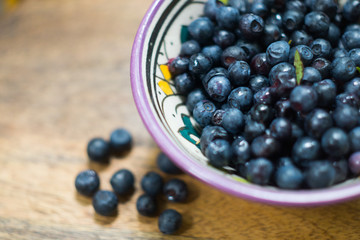 Ripe forest blueberries (bilberry, whortleberry, blaeberry, huckleberry) in a patterned bowl on a sunny summer day. Fresh organic berries
